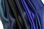 a close-up view of a collection of shiny, silky-looking fabric swatches in various colors, including blue, black, and dark blue.