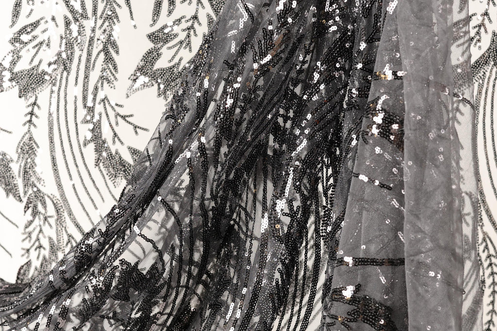 a close-up view of a black and white fabric with a pattern of sequins and beads, creating a visually striking and intricate design.