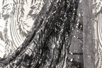 a close-up view of a black and white fabric with a pattern of sequins and beads, creating a visually striking and intricate design.