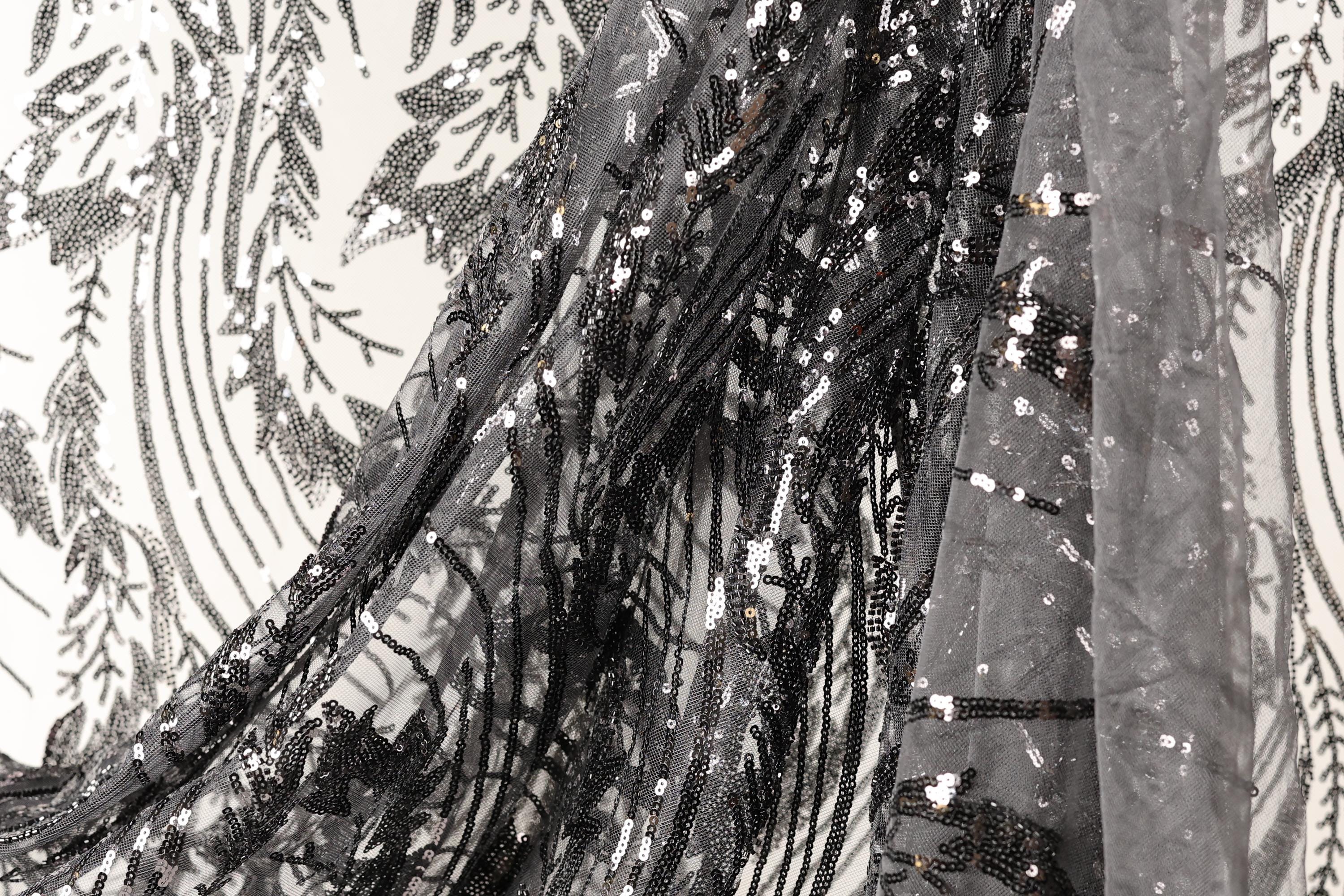 a close-up view of a black and white fabric with a pattern of sequins and beads, creating a visually striking and intricate design.