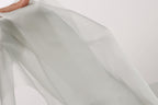 A hand is holding a piece of white fabric, which appears to be a sheer or sheer-like material.