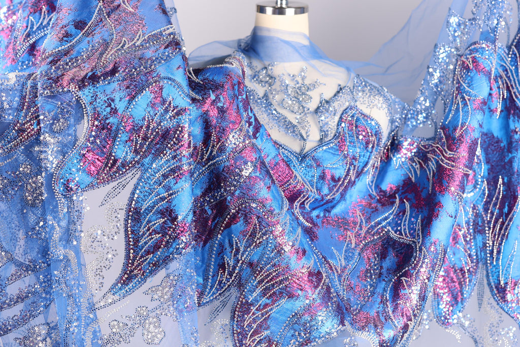 a close-up view of a fabric with a vibrant, colorful, and intricate design. The fabric appears to be a sheer material with a floral pattern in shades of blue, purple, and pink. The design is detailed and detailed, showcasing the craftsmanship and artistry of the fabric.