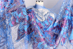 a close-up view of a fabric with a vibrant, colorful, and intricate design. The fabric appears to be a sheer material with a floral pattern in shades of blue, purple, and pink. The design is detailed and detailed, showcasing the craftsmanship and artistry of the fabric.