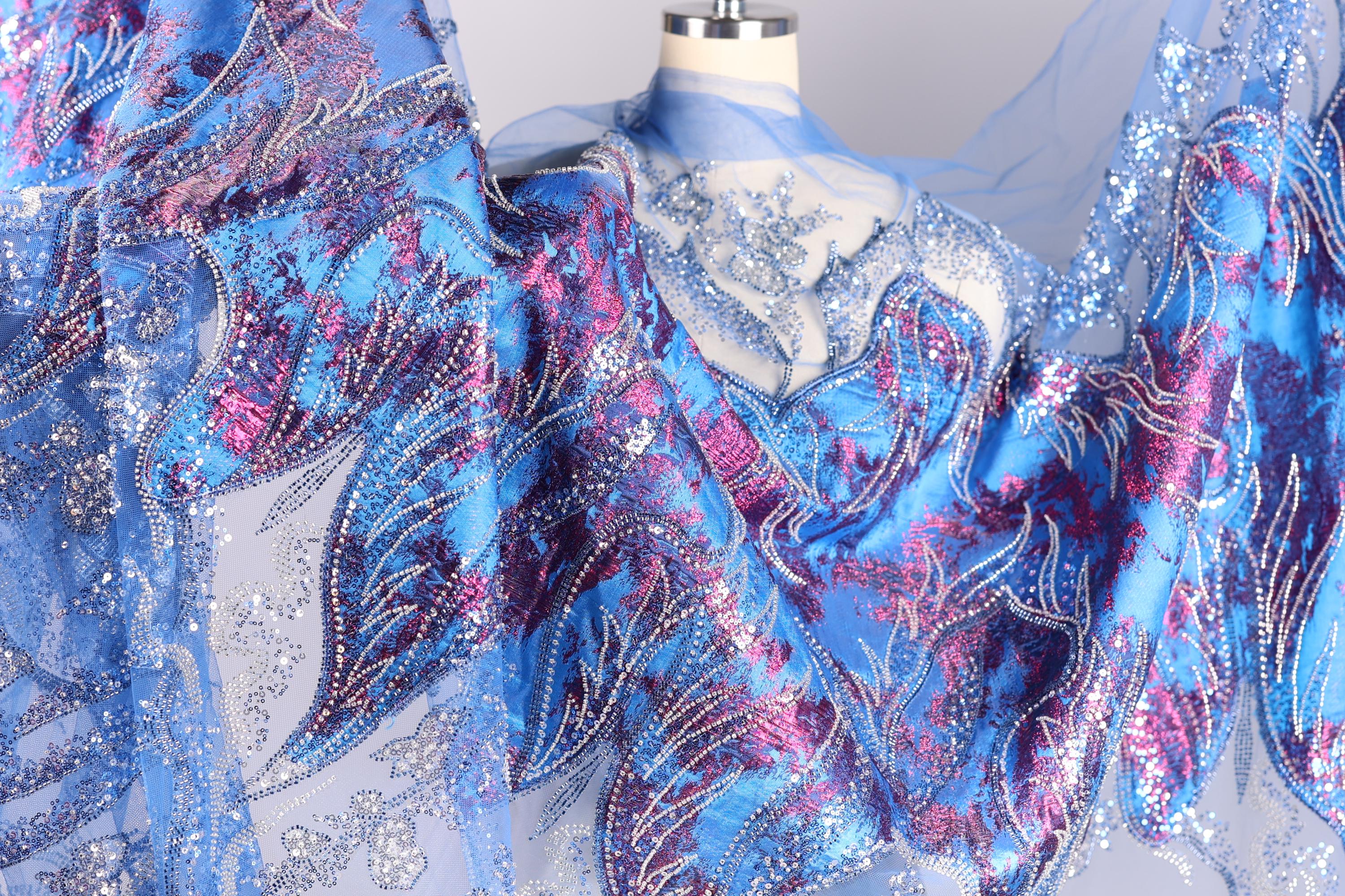 a close-up view of a fabric with a vibrant, colorful, and intricate design. The fabric appears to be a sheer material with a floral pattern in shades of blue, purple, and pink. The design is detailed and detailed, showcasing the craftsmanship and artistry of the fabric.