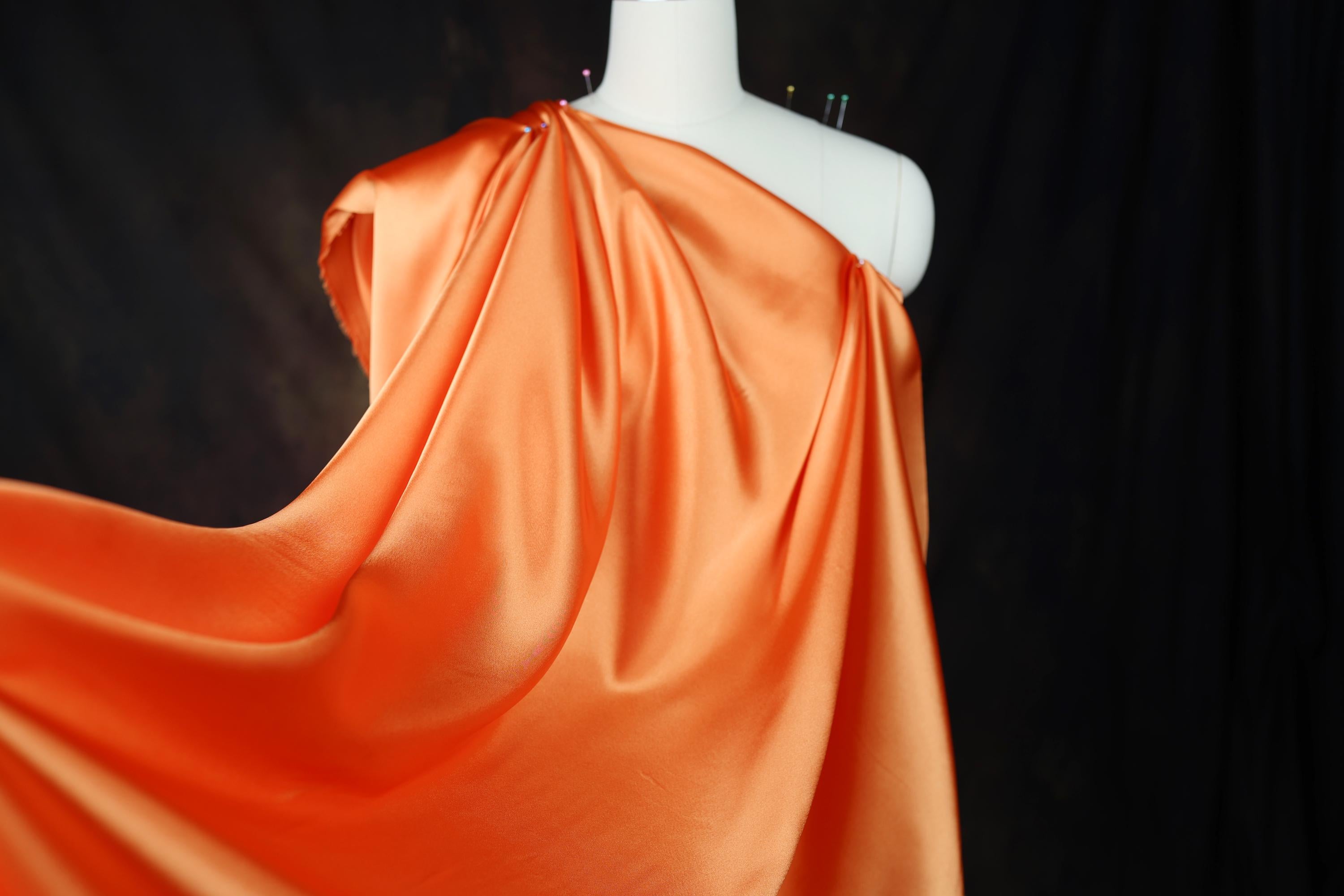 a mannequin wearing an orange dress on a black background