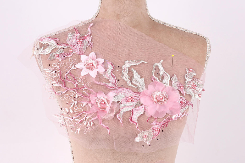 A mannequin wearing a pink floral dress with delicate pink and white flowers and leaves.