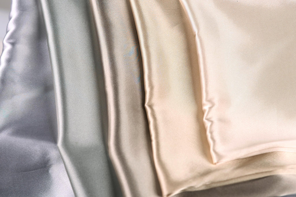 a close-up view of a collection of fabric swatches in various shades of gray, beige, and light brown.