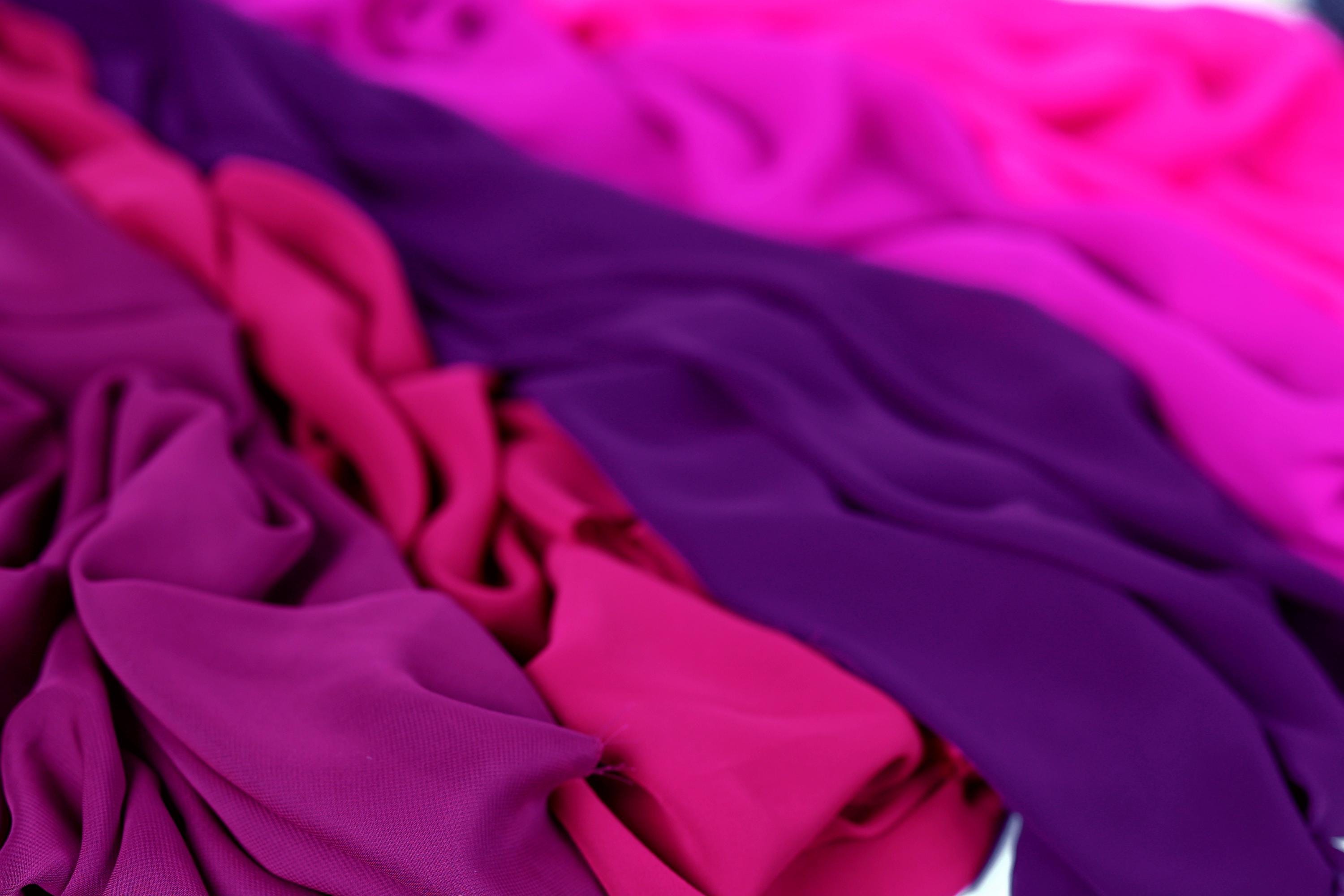 The image is a close-up of colorful fabric, with a mix of purple and pink hues. The fabric appears to be soft and flowing, creating a visually appealing and vibrant display.