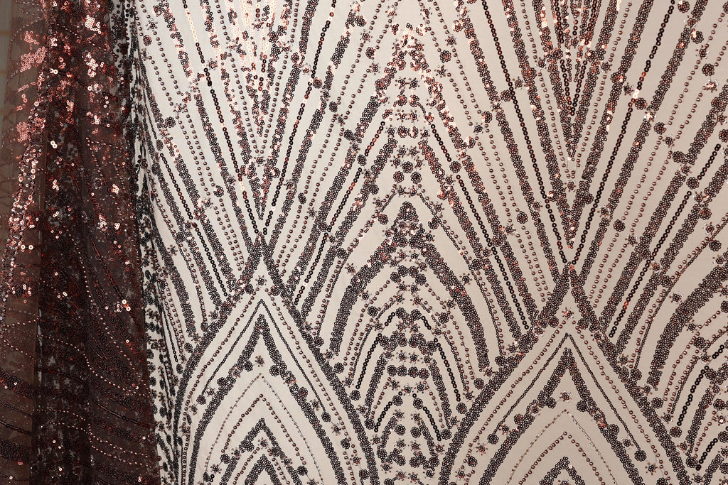 a close-up view of a fabric with a repeating pattern of sequin designs in shades of brown and black. The pattern appears to be a geometric design with a repeating diamond shape and lines, creating a visually striking and intricate design.