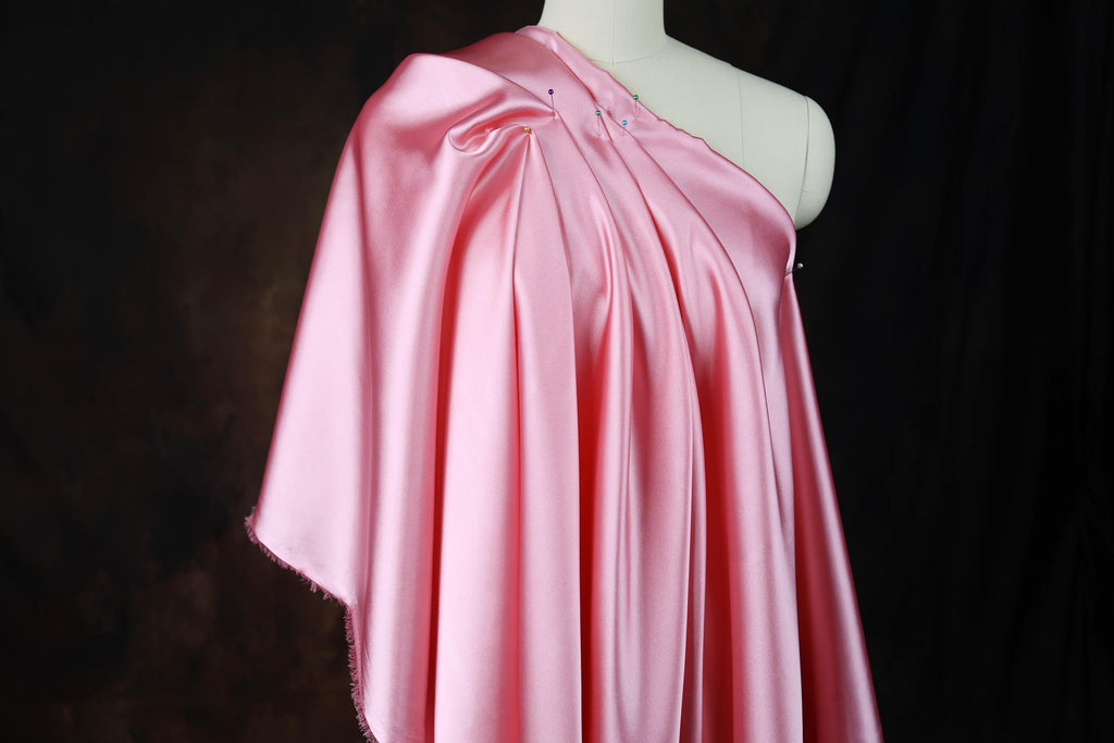 a pink dress on a mannequin with a black background