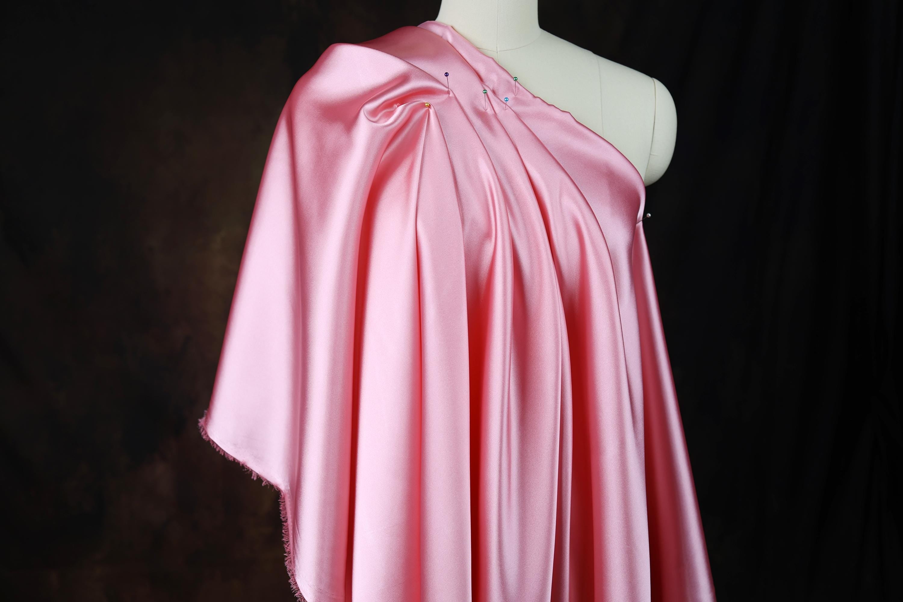 a pink dress on a mannequin with a black background