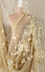 a mannequin wearing a gold sequin dress with a sheer, floral-patterned fabric draped over it.