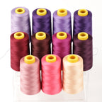 A collection of colorful spools of thread, including purple, pink, and yellow, arranged in a grid-like pattern.