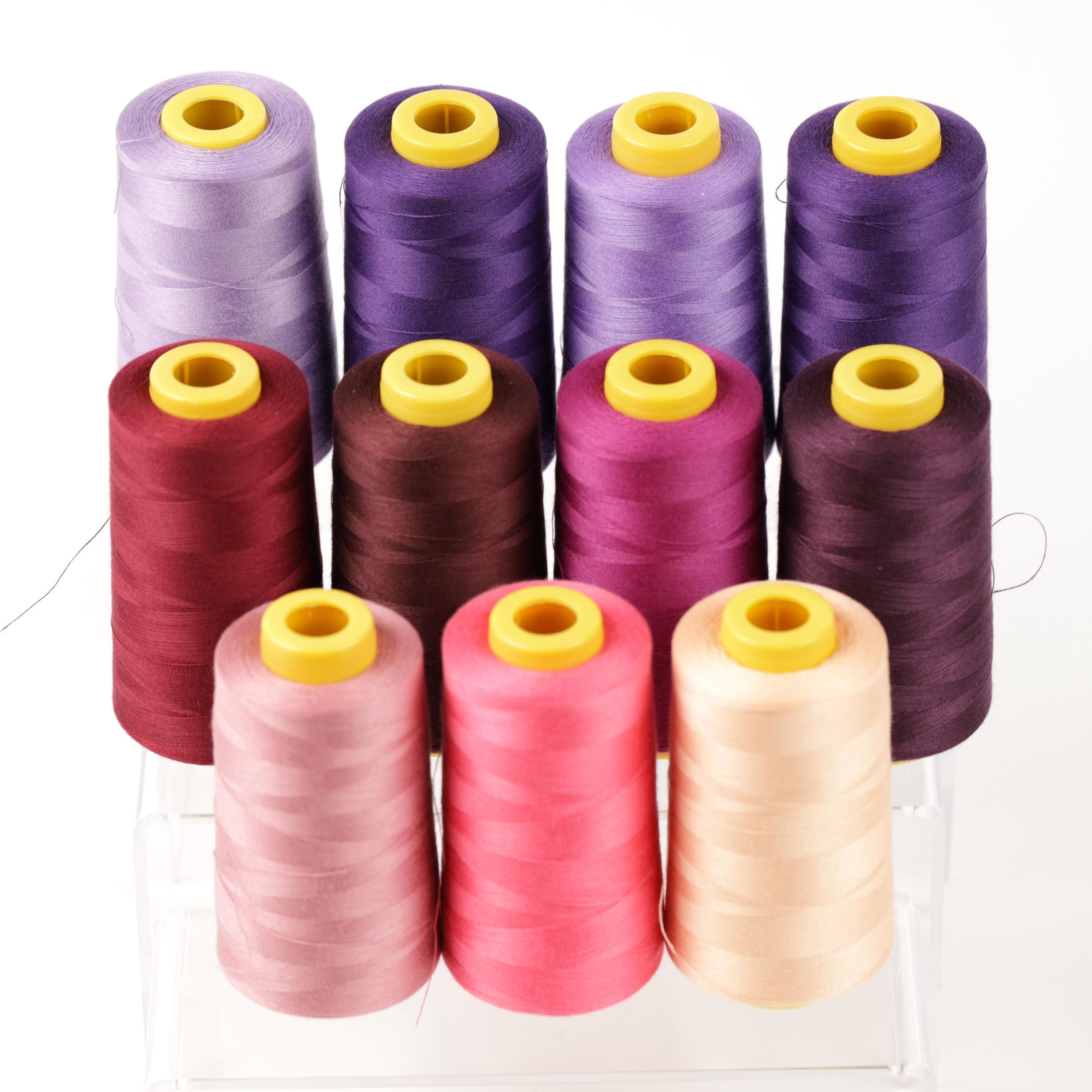 A collection of colorful spools of thread, including purple, pink, and yellow, arranged in a grid-like pattern.