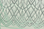 a close-up view of a fabric with a repeating pattern of green and black sequin designs. The pattern consists of various shapes and lines, creating a visually striking and intricate design. The fabric appears to be a light green color, which complements the green and black sequin pattern. The image does not contain any text or other discernible objects, and the focus is solely on the fabric and its detailed design.