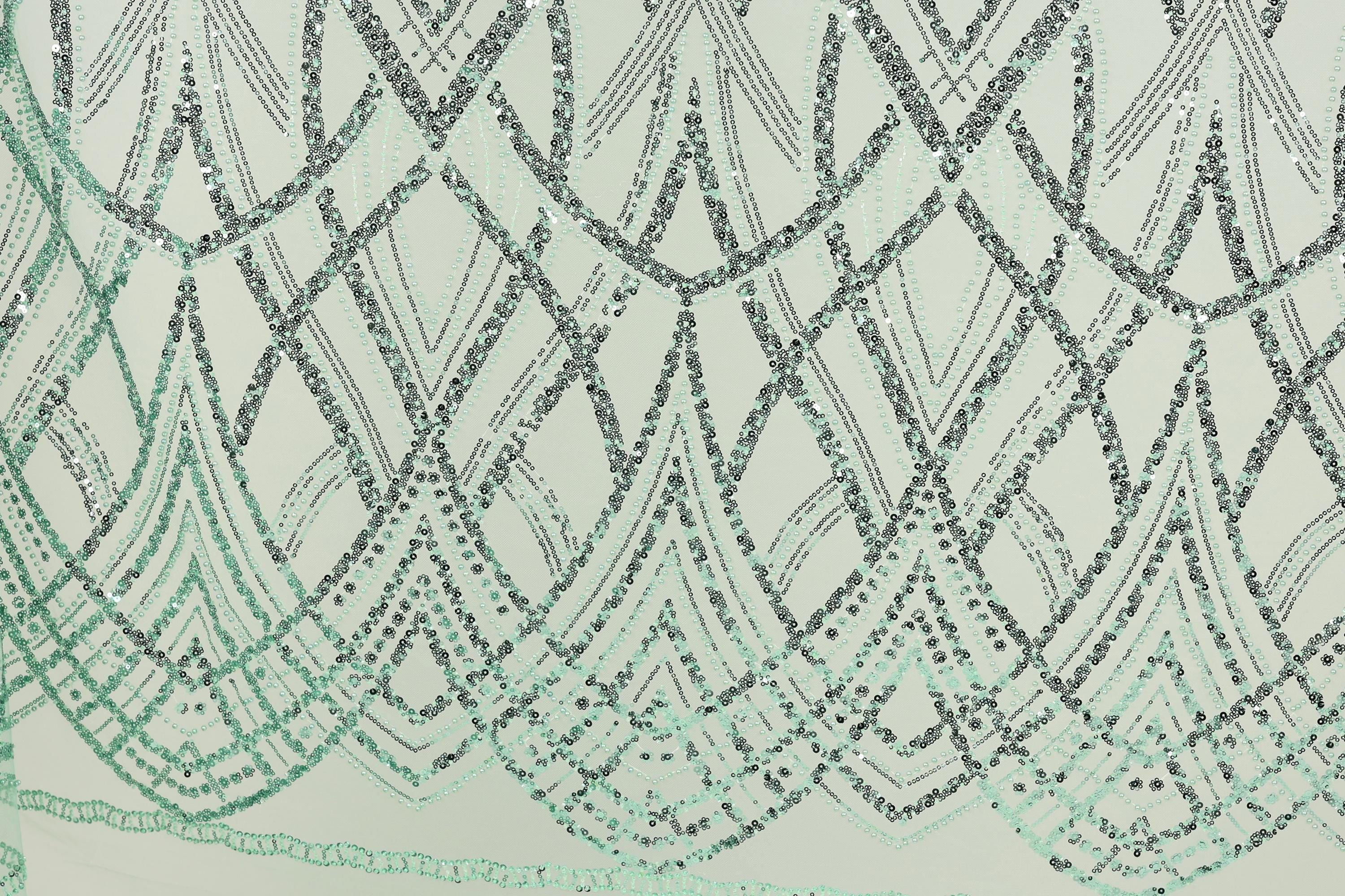 a close-up view of a fabric with a repeating pattern of green and black sequin designs. The pattern consists of various shapes and lines, creating a visually striking and intricate design. The fabric appears to be a light green color, which complements the green and black sequin pattern. The image does not contain any text or other discernible objects, and the focus is solely on the fabric and its detailed design.