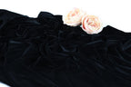 two pink roses resting on a crumpled black fabric.