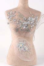 A mannequin with a beige body and a white dress form top, adorned with intricate silver and white floral embroidery.
