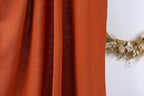 a close-up view of a red fabric, possibly a curtain or a piece of clothing, with a wreath of dried flowers or branches placed next to it on a white wall.