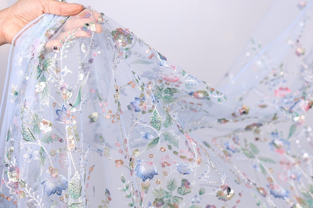 A hand is holding a piece of fabric with a floral pattern, featuring various colors and designs.