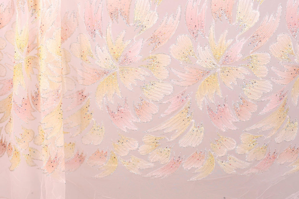 a close-up view of a fabric with a repeating pattern of pink and yellow flowers or leaves. The pattern is intricate and detailed, with the flowers or leaves appearing to be made of a shiny material, possibly sequin or glitter. The fabric has a soft and delicate appearance, suggesting it could be used for clothing or home decor.