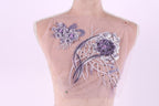 a mannequin with a delicate, intricate floral embroidery on its chest area. The embroidery is composed of various purple and white flowers, as well as some purple and white leaves, creating a visually appealing and detailed design.
