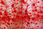 a close-up view of a fabric with a repeating pattern of red flowers and leaves, creating a vibrant and eye-catching design.
