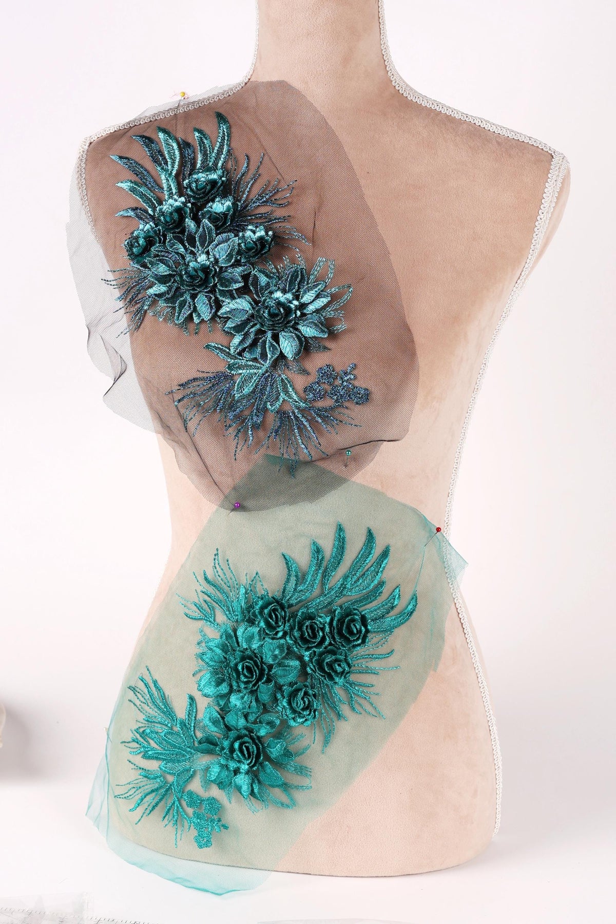 A mannequin with a floral design on its back, featuring a combination of green and blue flowers and leaves.