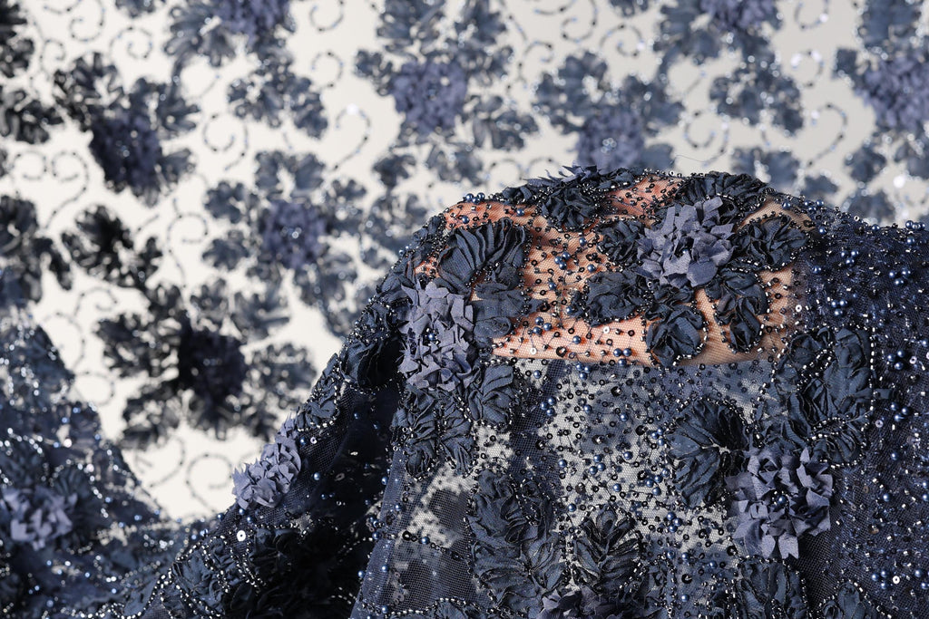 a close-up view of a fabric with intricate blue floral designs and beading, creating a visually striking and detailed appearance.