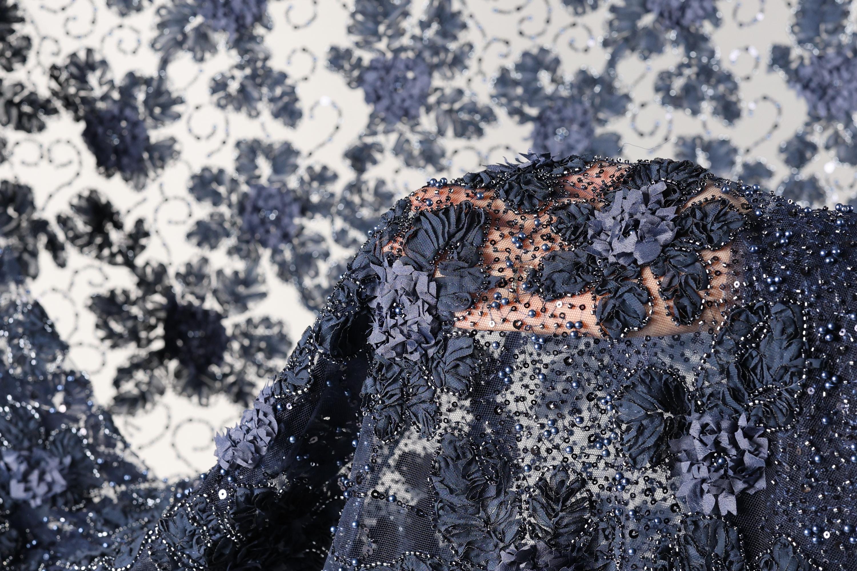 a close-up view of a fabric with intricate blue floral designs and beading, creating a visually striking and detailed appearance.
