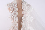 A close-up view of a white lace wedding veil with intricate floral patterns.