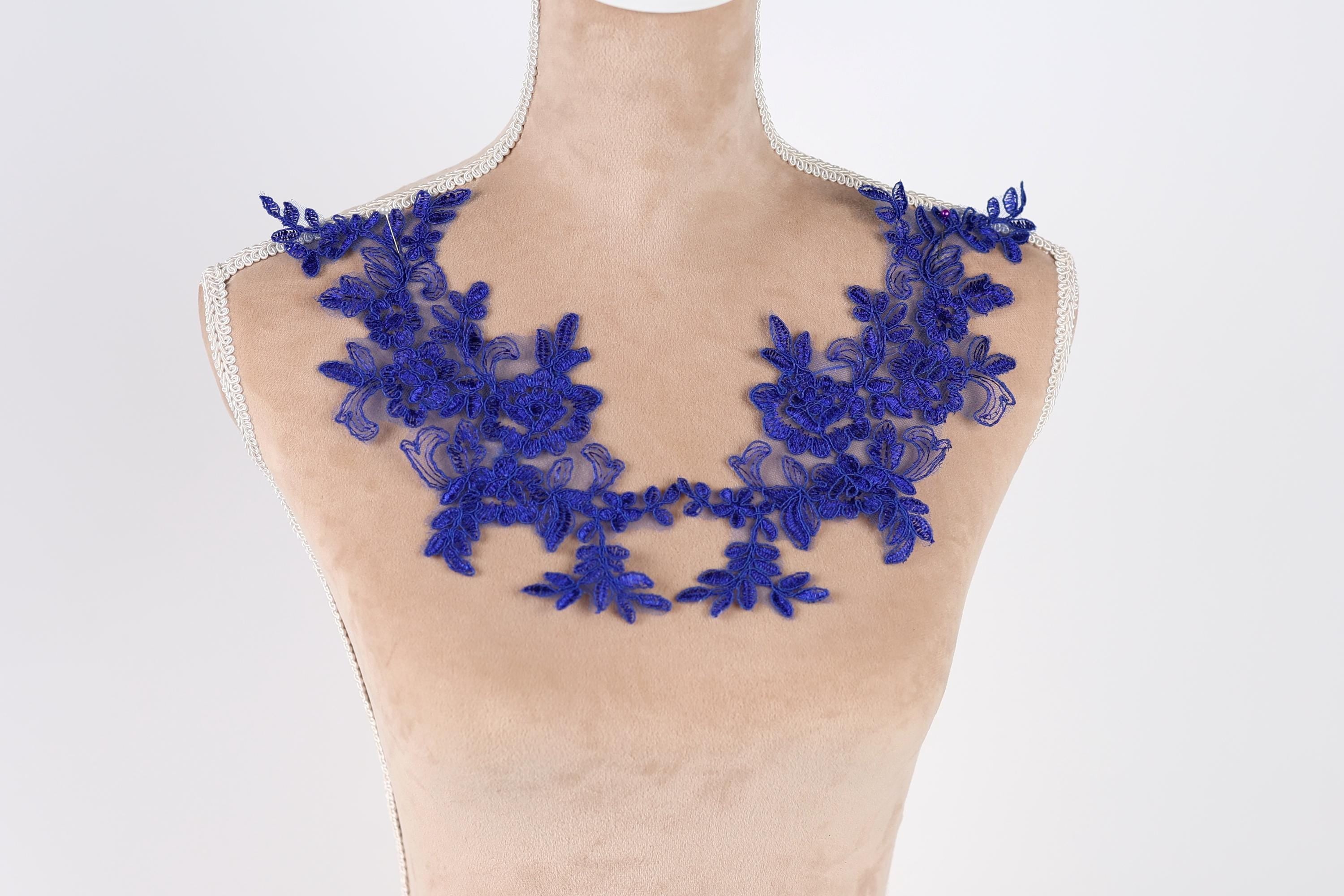 A mannequin wearing a necklace with blue floral embroidery.