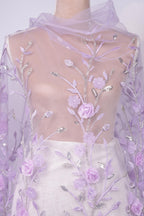a dress with a sheer, floral-patterned fabric. The dress has a white skirt and is adorned with delicate purple flowers and leaves, creating a visually appealing and elegant design.