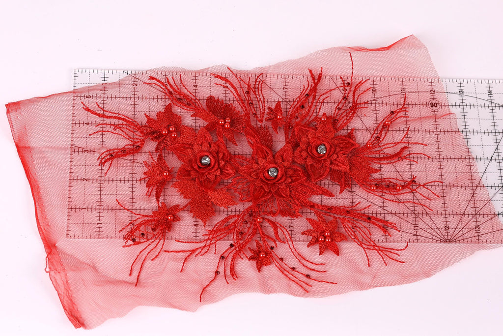 a red floral embroidery with a clear measuring tape on a pink background.