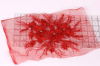 a red floral embroidery with a clear measuring tape on a pink background.