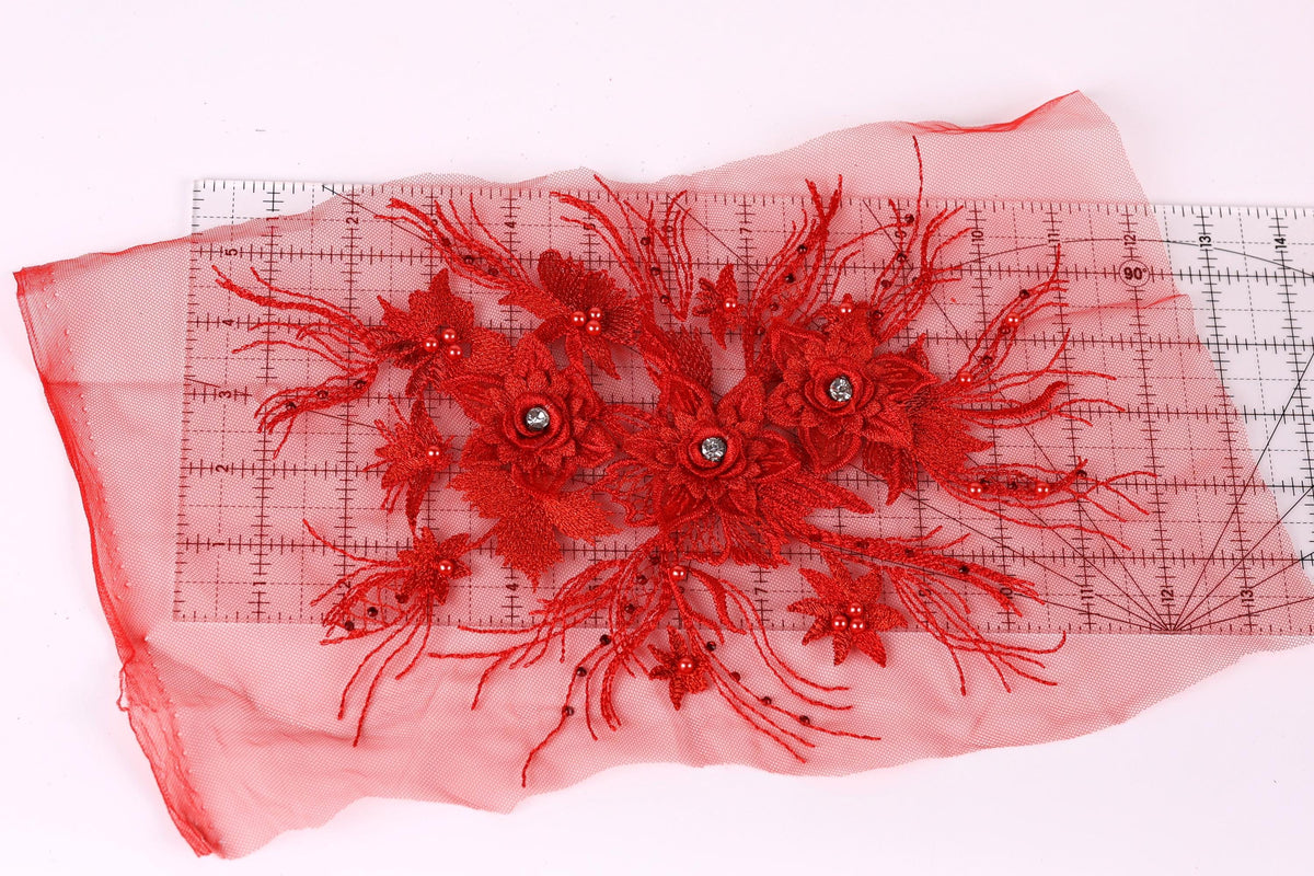 a red floral embroidery with a clear measuring tape on a pink background.