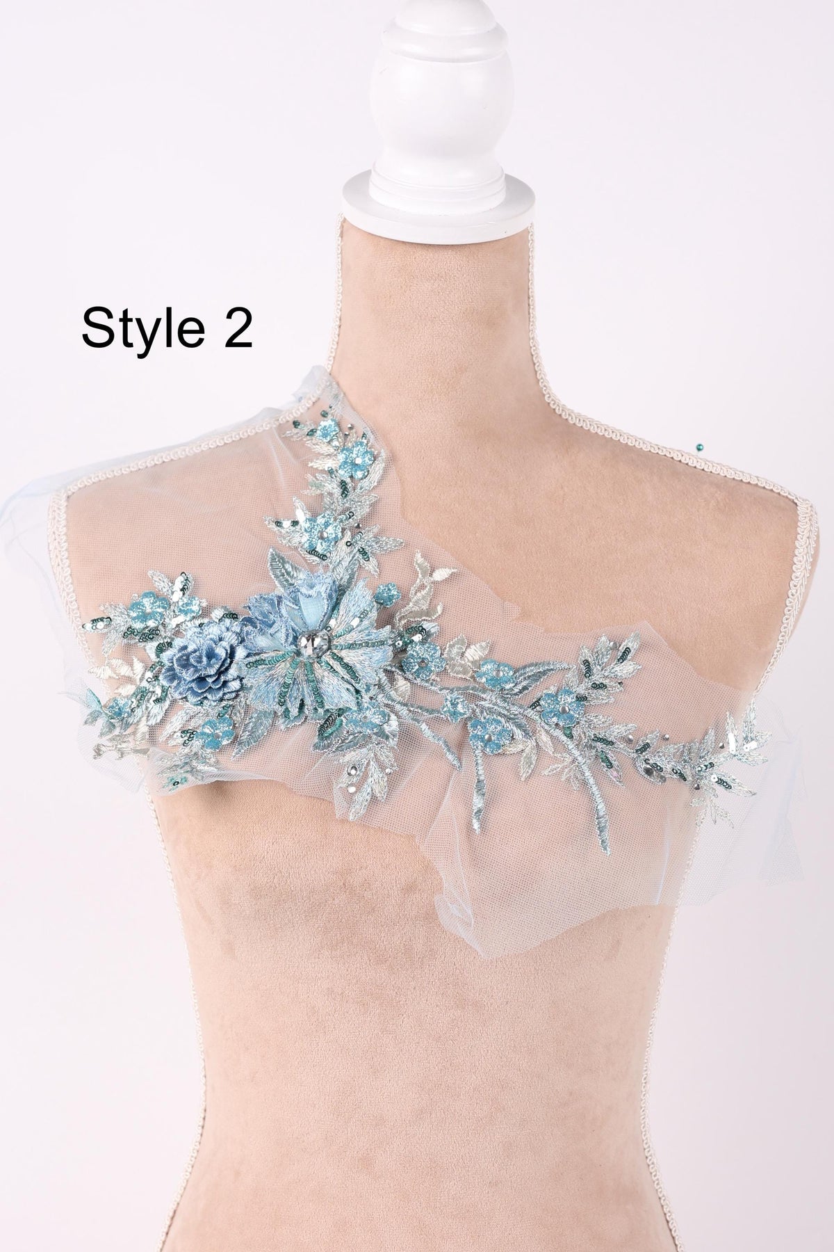 A mannequin wearing a dress with a floral embellishment on the shoulder.