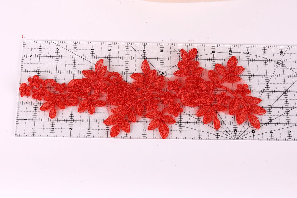 a clear ruler with red floral embroidery designs placed on it.