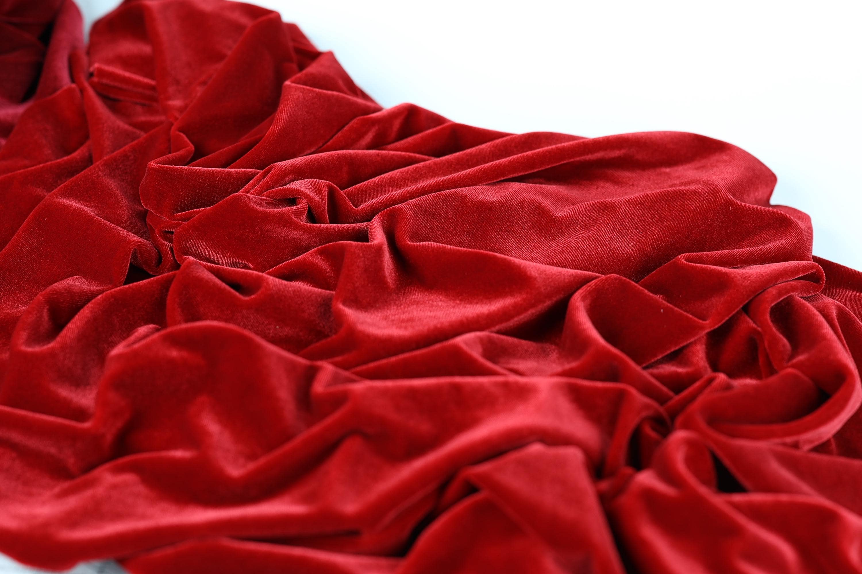 a close-up view of a crumpled red velvet fabric, with its folds and creases clearly visible.