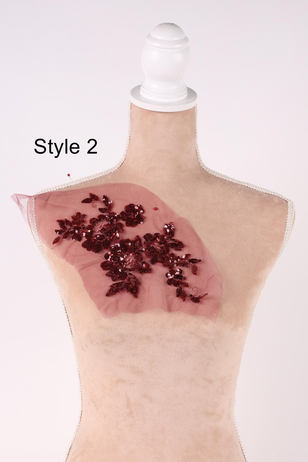 A mannequin head with a pink fabric draped over it, featuring a decorative floral pattern in red and white.