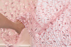 A hand is holding a piece of fabric with a pink floral pattern, which appears to be a close-up view of the fabric.