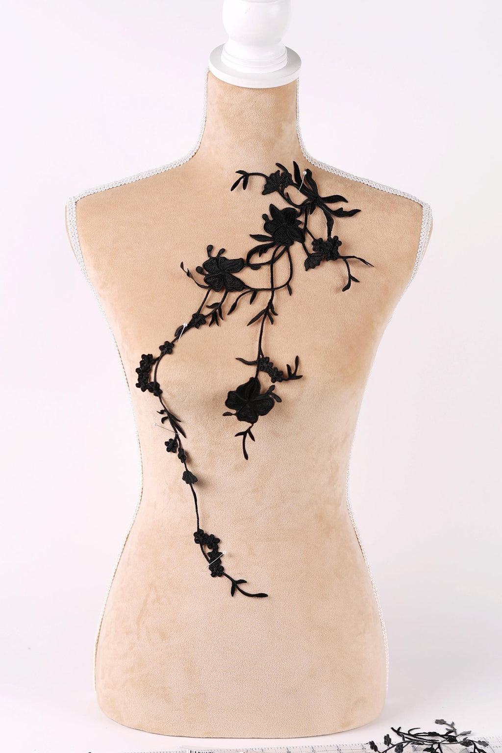 A mannequin with a beige body and black floral embroidery on its bust area.