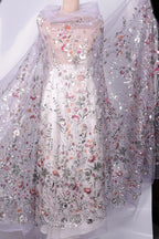 a long, white dress with a sheer, floral-patterned fabric draped over it. The dress has a sheer, transparent overlay that adds an elegant and delicate touch to the overall design.