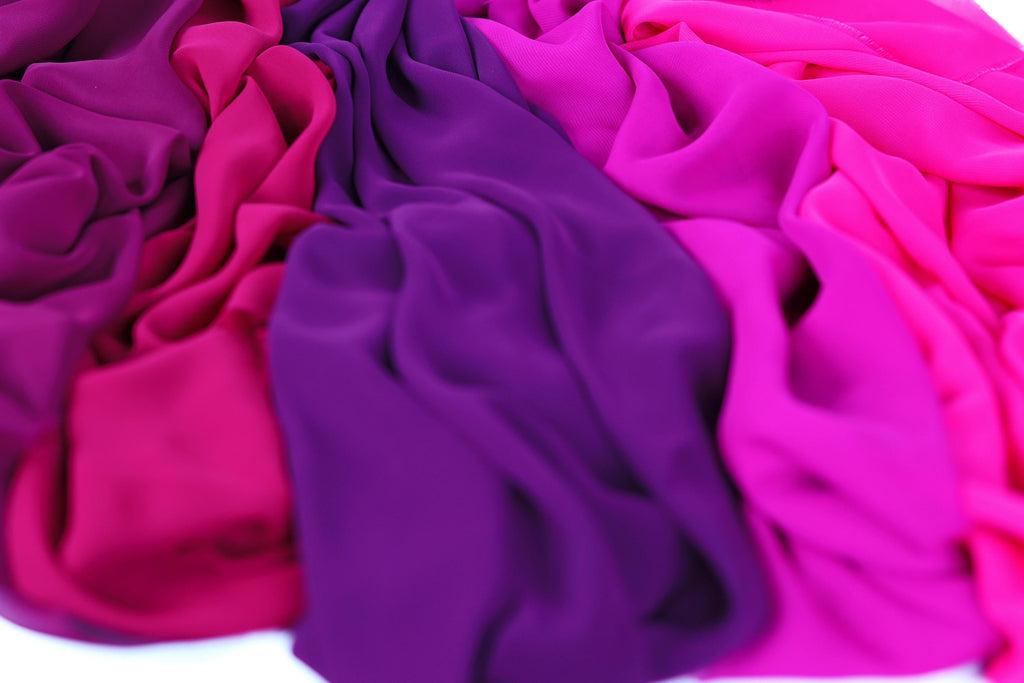 a close-up view of colorful fabric, with a mix of pink, purple, and blue hues. The fabric appears to be soft and flowing, creating a visually appealing and vibrant display.