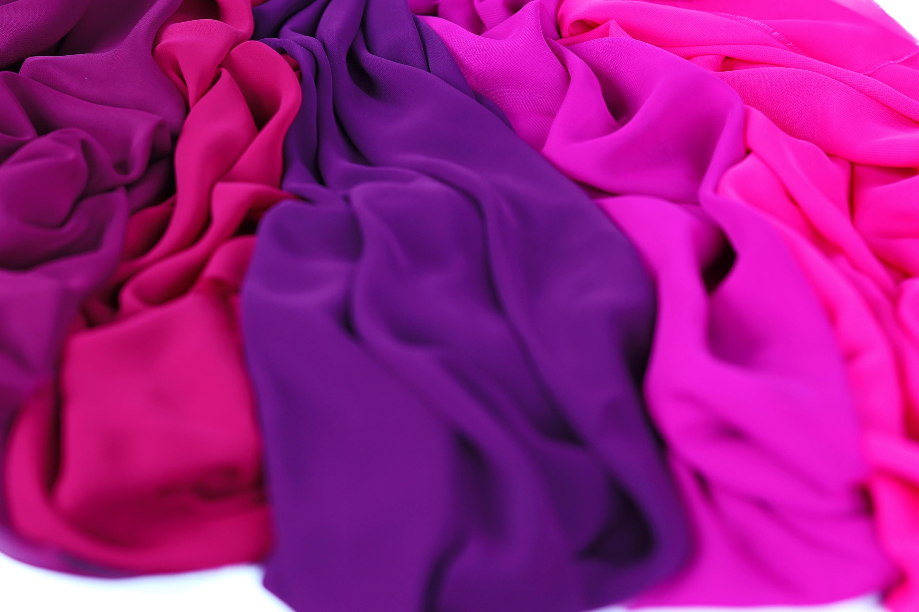 a close-up view of colorful fabric, with a mix of pink, purple, and blue hues. The fabric appears to be soft and flowing, creating a visually appealing and vibrant display.