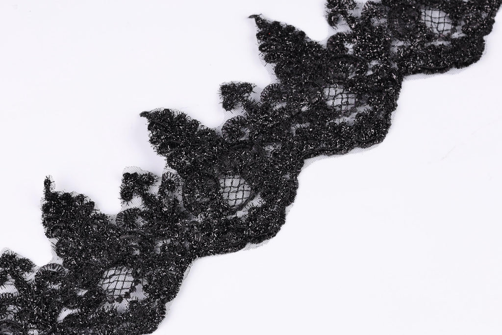 a close-up view of a black lace trim or ribbon, with intricate patterns and textures.