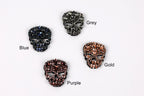 four different colored skull-shaped buttons, each with a unique design and color.