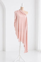 A mannequin wearing a pink one-shoulder dress with a draped, flowing fabric draped over the shoulder.