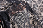 a close-up view of a black lace fabric with intricate floral patterns. The fabric appears to be made of sheer material, giving it a delicate and elegant appearance.