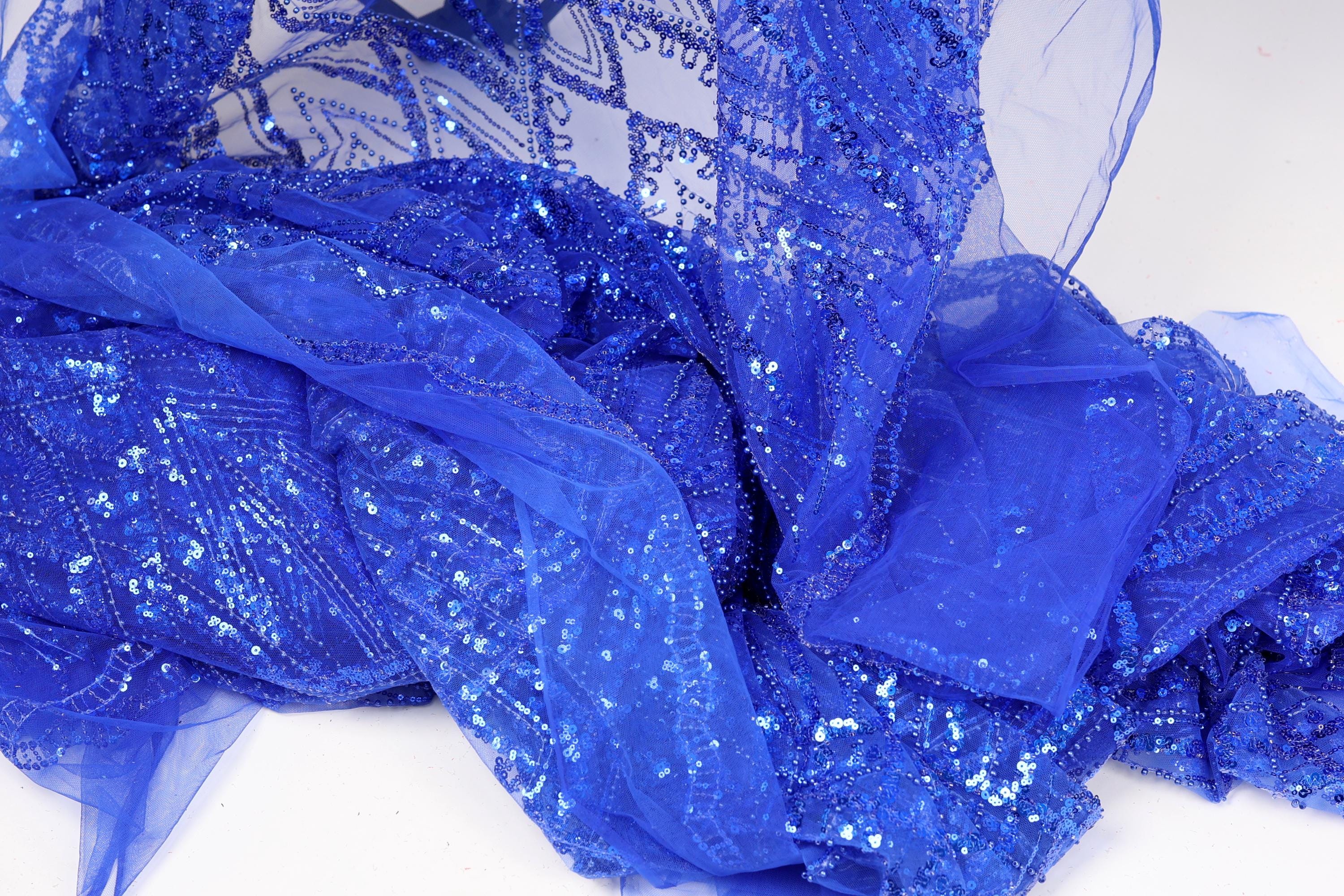 a close-up view of a piece of blue sequin fabric, with its intricate patterns and sparkling texture clearly visible.